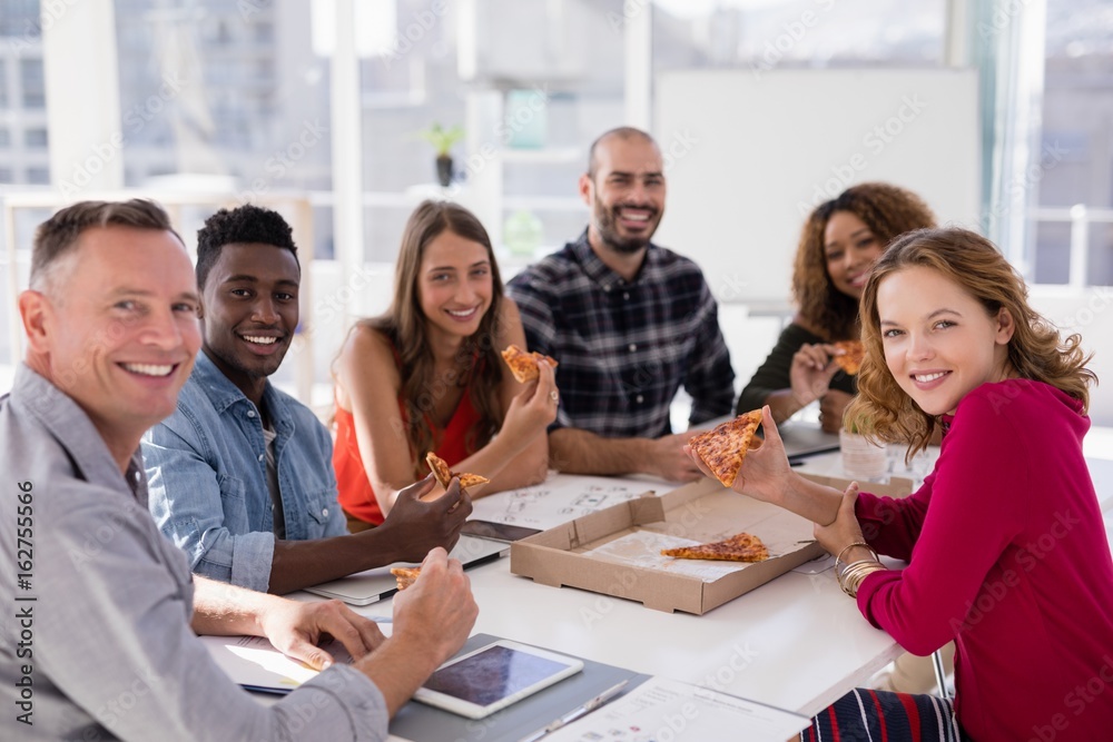 Fototapeta premium Portrait of executives having pizza in conference room