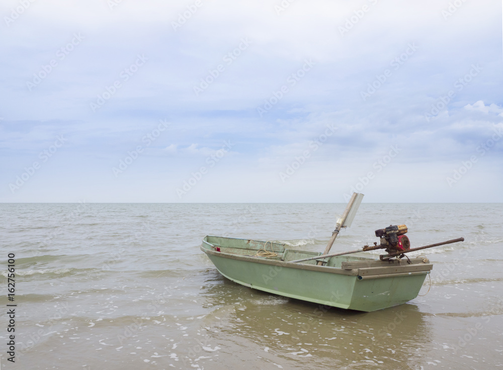 Green small fishing boat in the sea and sky background.