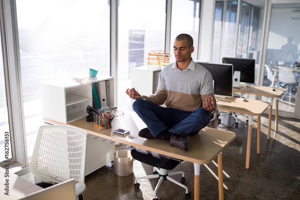 Male executive doing yoga in office Male executive doing yoga in office
