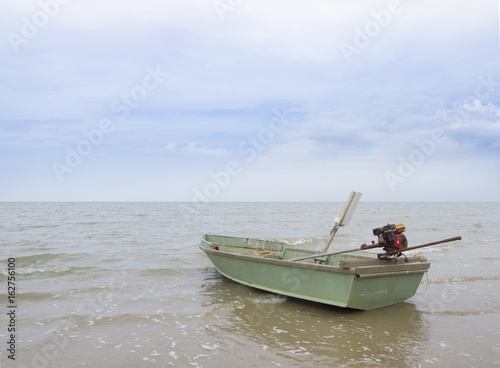 Green small fishing boat in the sea and sky background.