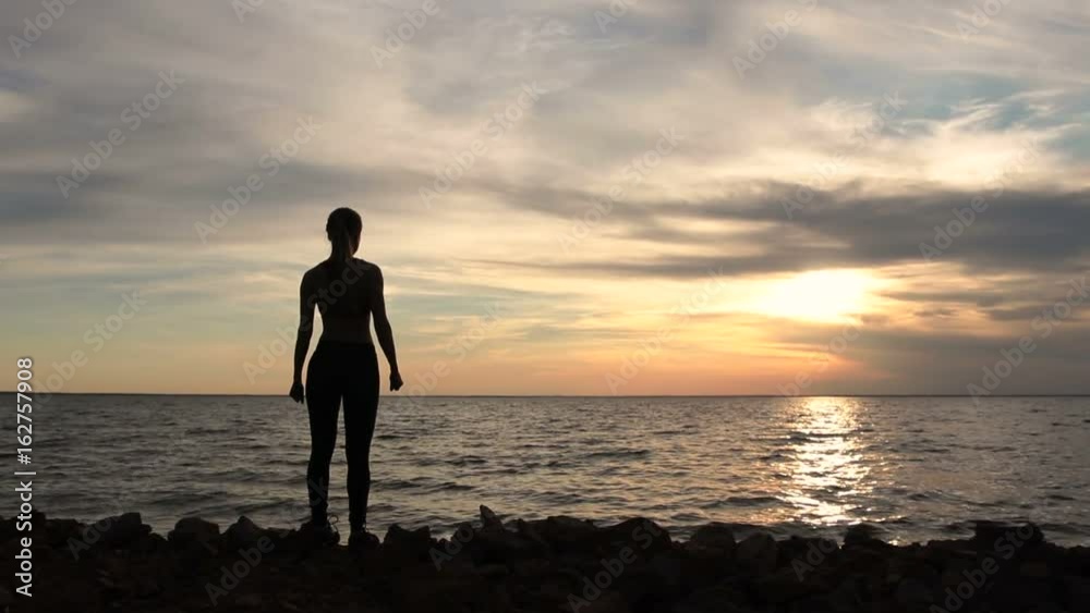Woman cheering celebrating success at beach sunset