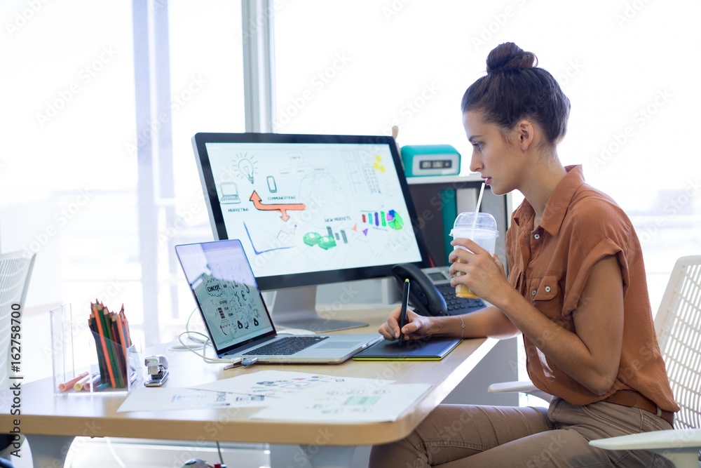 Female executive working over graphic tablet at her desk Female executive working over graphic tablet at her desk