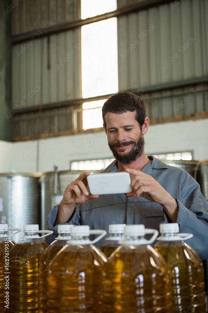 Smiling working taking a photo of olive oil bottles Smiling working taking a photo of olive oil bottles