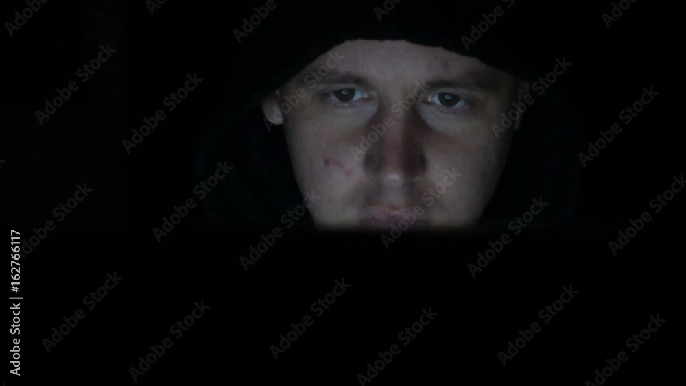 Male hacker working on a computer in a dark office room. Male hacker working on a computer in a dark office room.
