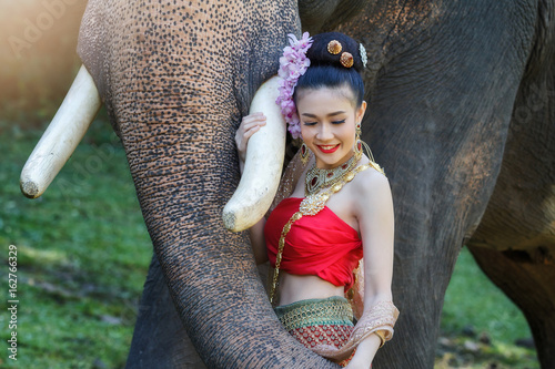 Pretty girl in traditional thai costumes touching elephant's trunk