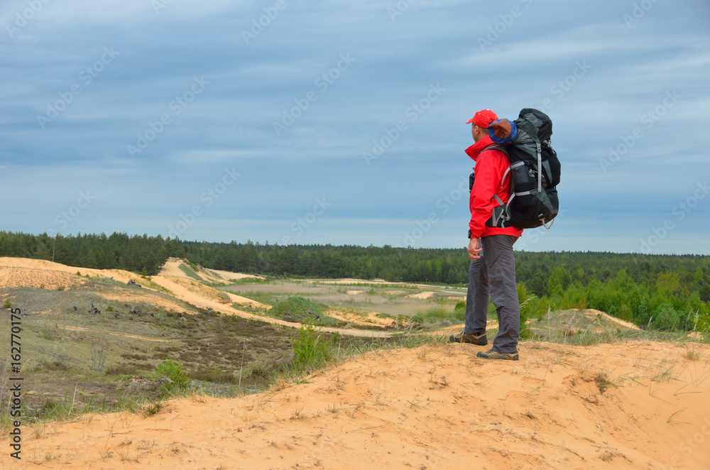 The tourist is looking around standing on the high dune.