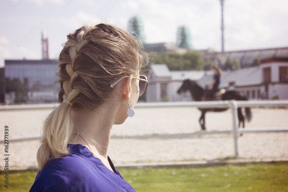 the girl looks at the horse with rider