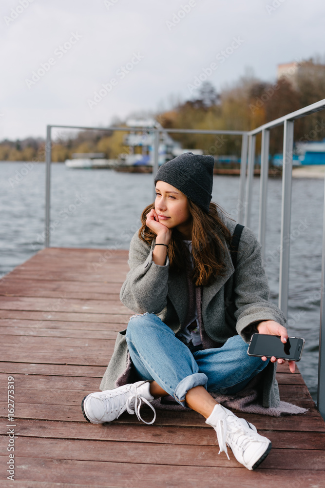 Young pretty girl on wooden bench on old pier