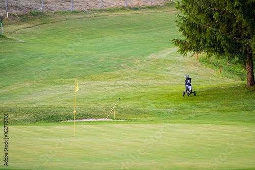 Golf course with one flag pole and trolley on fairway