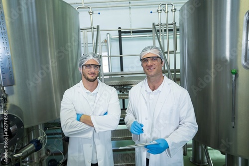 Portrait of scientists standing by storage tank