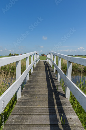 White small bridge with blue sky and farm © Daan