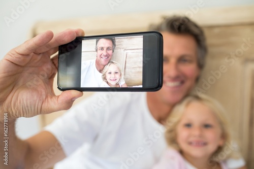 Father and daughter taking selfie on mobile phone in bedroom