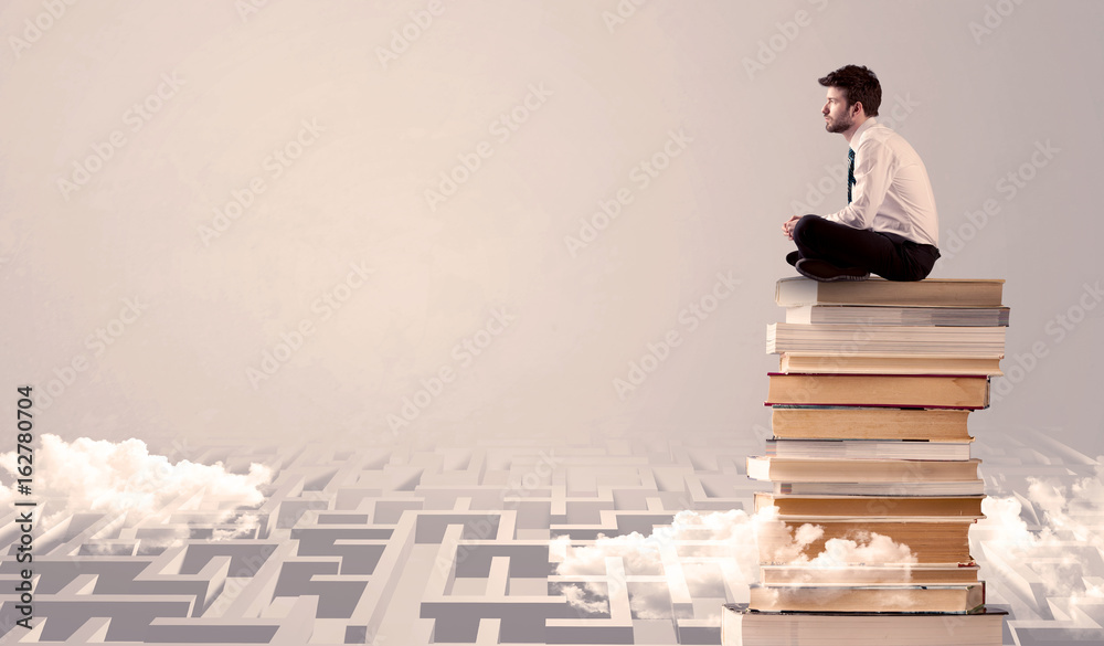 Businessman sitting on books in labirynth Businessman sitting on books in labirynth