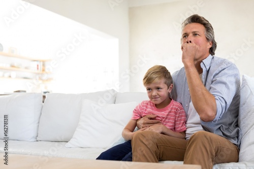 Father and son watching tv in living room