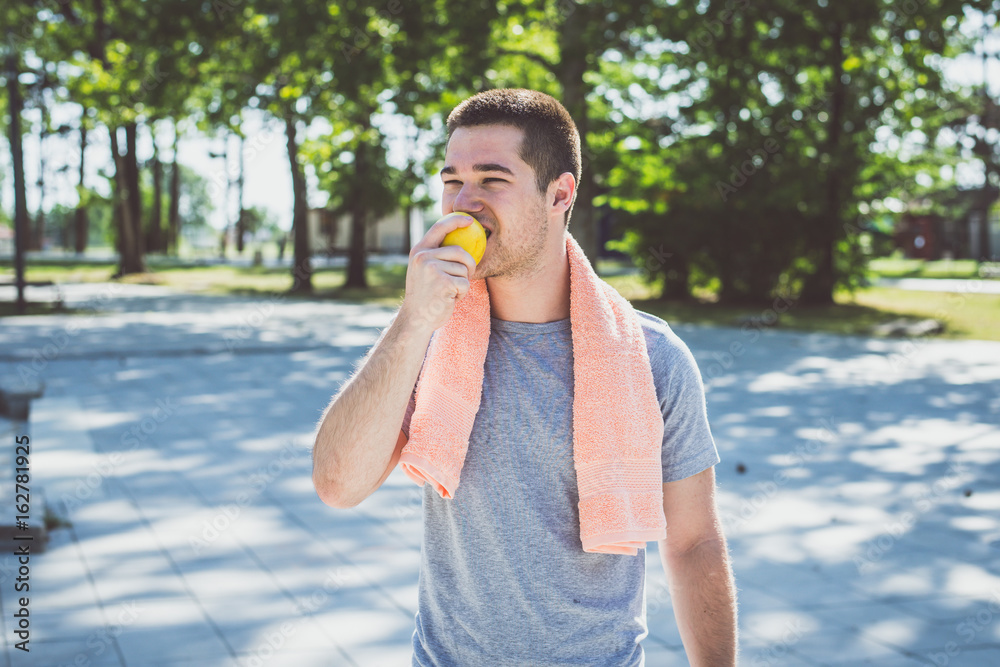 Fototapeta premium Male Runner eat apple in a Park
