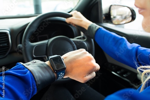 Cropped image of woman looking at smart watch during test drive