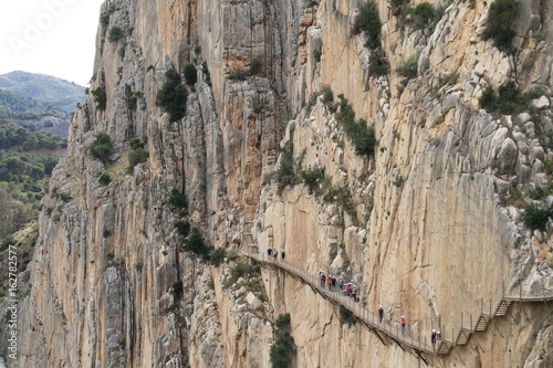Hikers walking along the wooden walkways of the gorge of Los Gaitanes, in the Caminito del Rey, Malaga, Spain