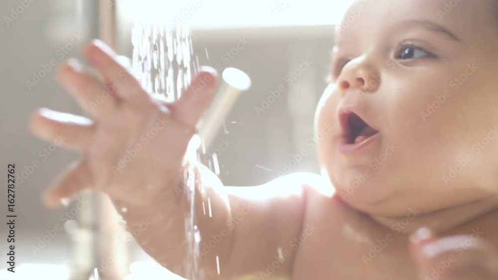 Baby in Sink Bathing and Playing with Water Laughing. close up of baby playing in sink with water from faucet in slow motion

