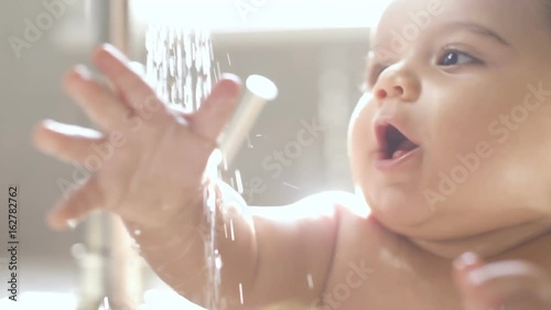 Baby in Sink Bathing and Playing with Water Laughing. close up of baby playing in sink with water from faucet in slow motion

