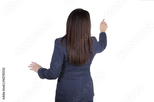 Woman in business attire touching an imaginary touch screen. Isolated on white background back view