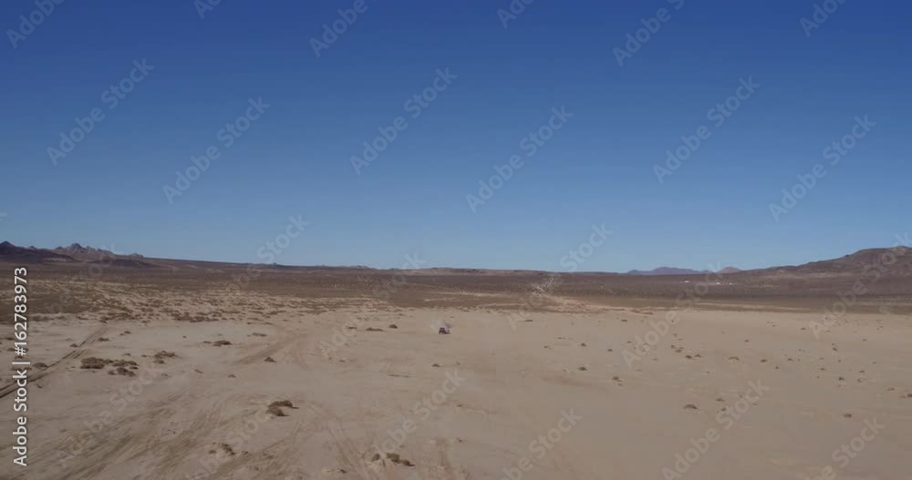 Aerial drone shot of off-road 4x4 race truck driving through desert Aerial drone shot of off-road 4x4 race truck driving through desert