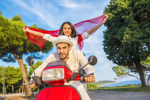 Happy free freedom couple driving scooter excited on summer holidays vacation.