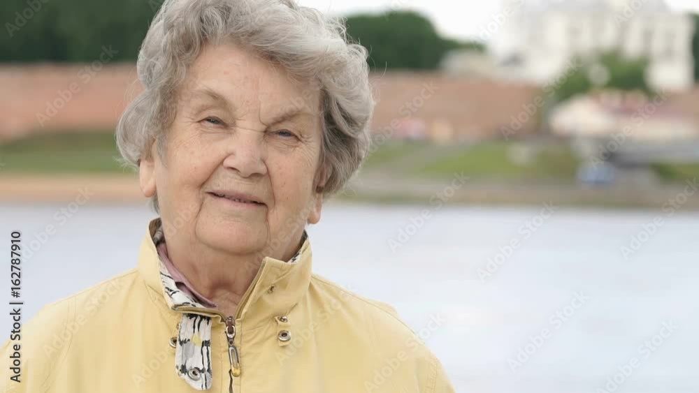 Portrait of smiling mature old woman aged 80s outdoors. Slow Motion Portrait of smiling mature old woman aged 80s outdoors. Slow Motion