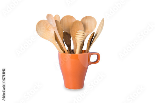 Kitchen cooking utensils in ceramic cup on wooden background.