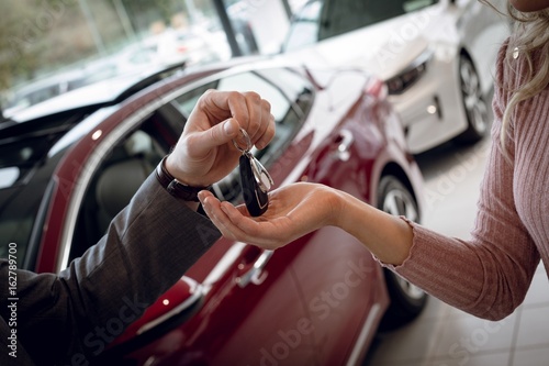 Close up of salesman giving car keys to female customer