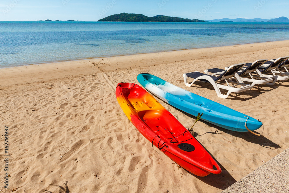 Two colorful empty canoe red and blue on the beach. Two colorful empty canoe red and blue on the beach.