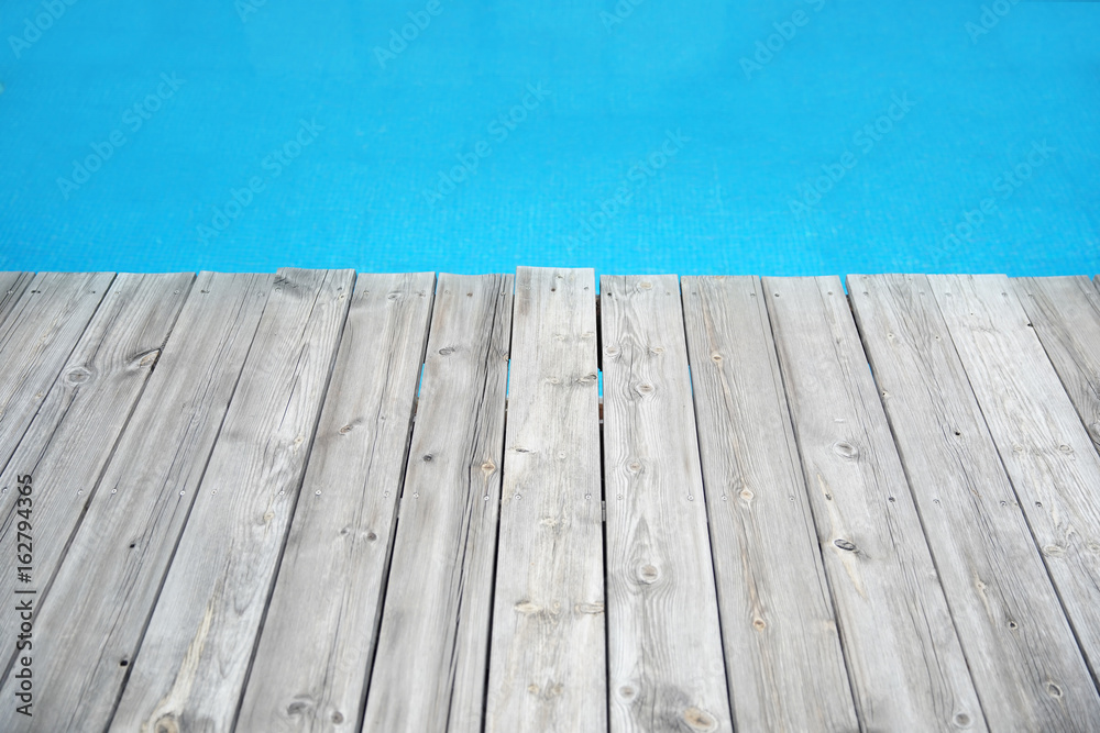 Wood plank pier against blue water Wood plank pier against blue water