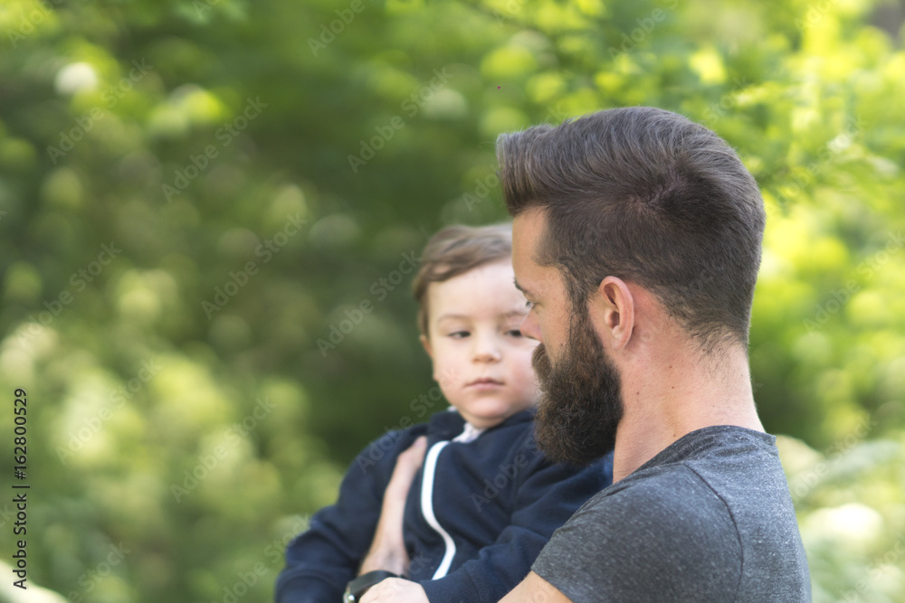 Young bearded hipster father holding his little son in park Young bearded hipster father holding his little son in park
