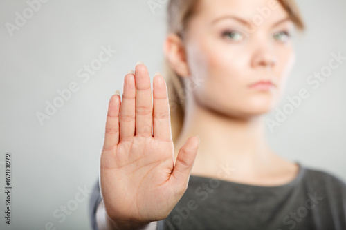 Female shows stop sign by her hand.