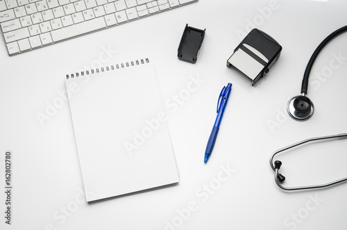 Top view of modern, sterile doctors office desk. Medical accessories isolated on a white table background with copy space around products. Photo taken from above.