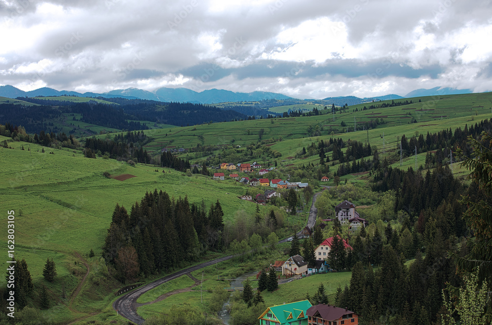 View from a height of a winding road passing through the Carpathian village