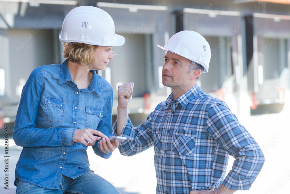 male architect showing something to colleague outdoors
