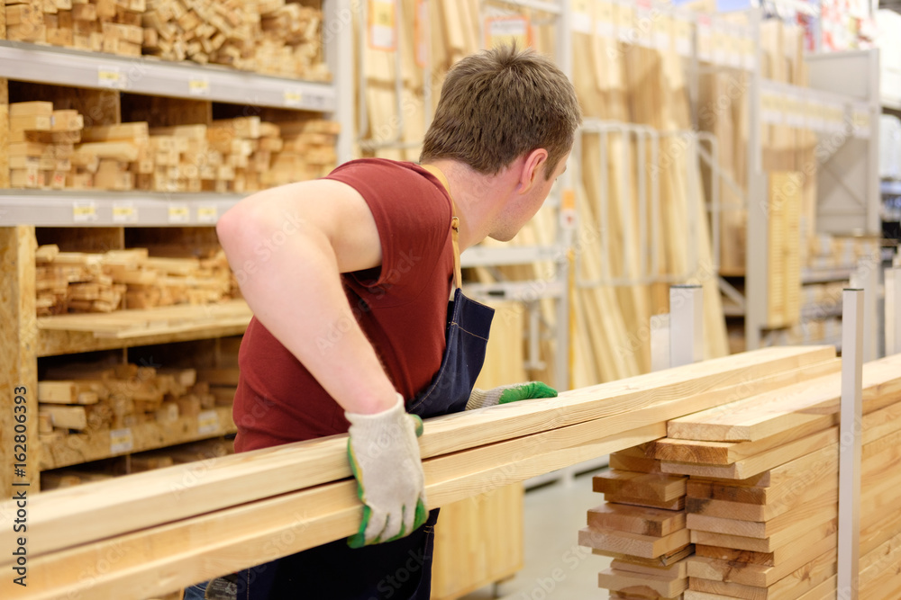 worker or seller in construction store or warehouse wood department at work