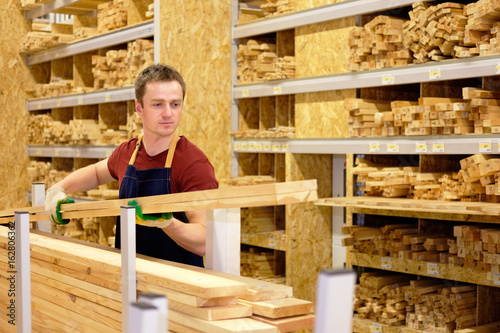 Fotografie worker or seller in construction store or warehouse wood section at work