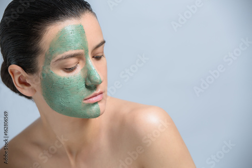 Young woman applaying green face mask - studio portrait photo