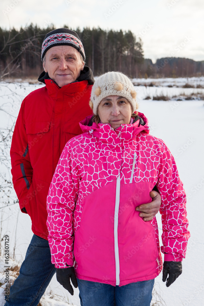 Husband and his wife in warm clothes standing together in winter forest