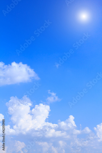 Blue sky background with white clouds and sunshine on sunny summer or spring day.