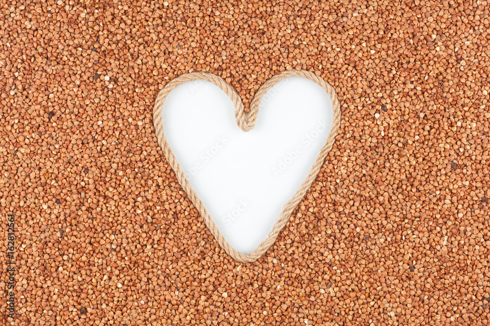 Buckwheat grains and a rope in the shape of a heart with a place for designers. Buckwheat grains and a rope in the shape of a heart with a place for designers.