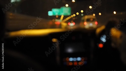 Driving at night time in city. Out of focus with blurry from windshield view and blurred cars in city bokeh light.