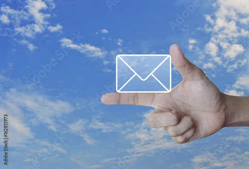 Mail icon on finger over blue skywith whie cloud, Contact us concept
