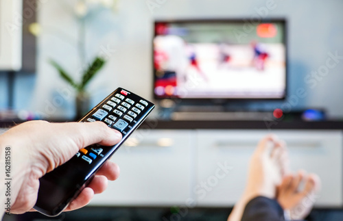 Men with the remote control, front of the television. photo