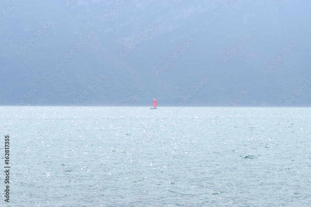 Lake Iseo and red sailboat in the small fog, horizontall format