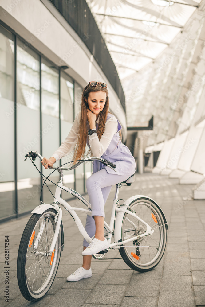 Full length shot of a beautiful young businesswoman with her bike going to work. Beauty with white vintage bike.
