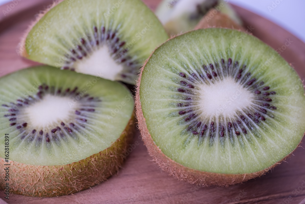 Whole kiwi fruit and sliced segments on wooden plate. Whole kiwi fruit and sliced segments on wooden plate.