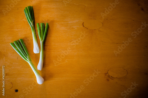 Three bunches of green onion on table
