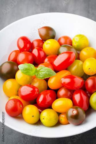 Tomatoes an gray background. Colorful tomatoes  red tomatoes  yellow tomatoes  orange tomatoes  green tomatoes. Colour tomatoes on the gray background.